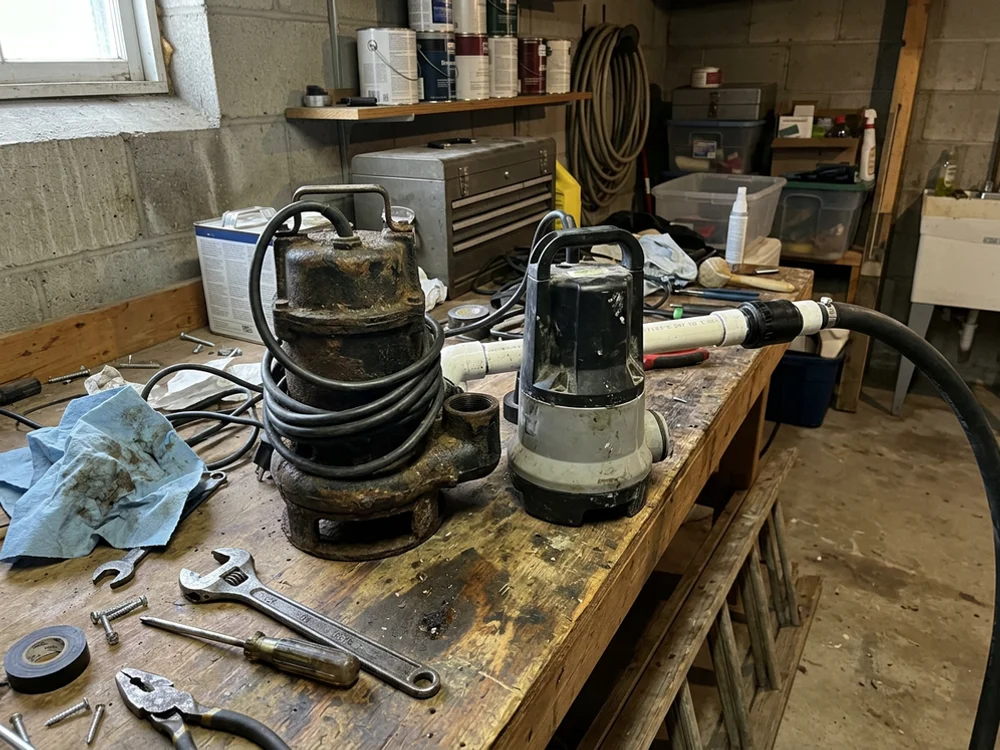Cast iron and plastic sump pumps side by side on a workbench
